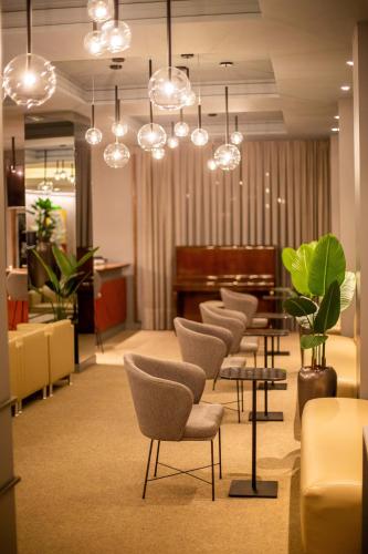 a waiting room with a row of chairs and a piano at Hotel Metrópole Maringá in Maringá