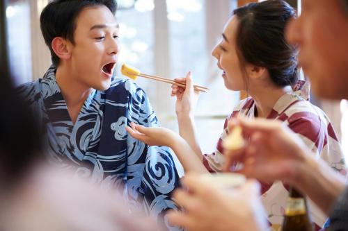 a group of people sitting around a table eating food at Kansyokan in Mogami