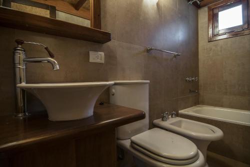 Un baño con lavabo, inodoro y bañera. en La Tavola Hotel, en Pinamar