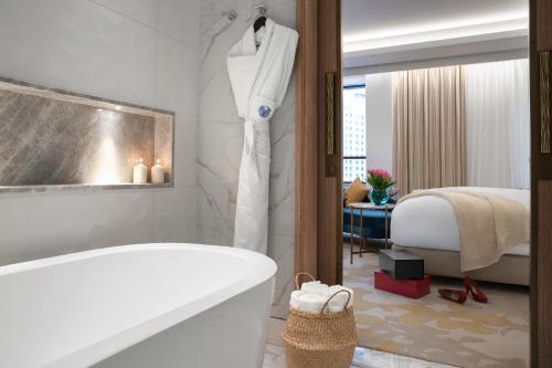 a bathroom with a bath tub and a bedroom at Al Jaddaf Rotana Suite Hotel in Dubai