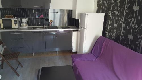 a kitchen with a purple couch in front of a refrigerator at Appartement JARDINS DU LOUVRE in Paris