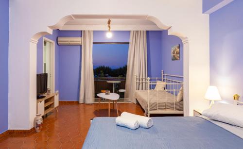 1 dormitorio con paredes azules, 1 cama y TV en CHAMBRE BLEUE en Ialyssos