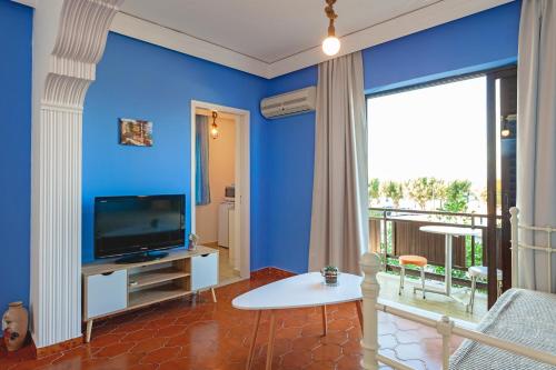 sala de estar con paredes azules y TV en CHAMBRE BLEUE en Ialyssos