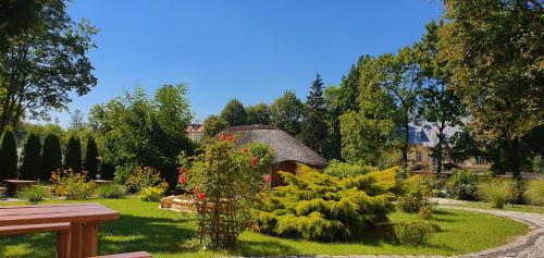 a garden with a thatch roof and some plants at Villa Carmen in Kudowa-Zdrój