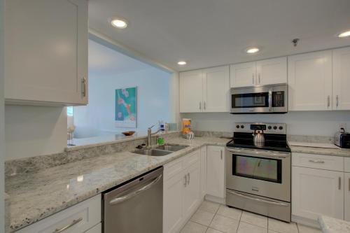 a kitchen with white cabinets and stainless steel appliances at Anna Maria Island Beach Sands 101 in Bradenton Beach
