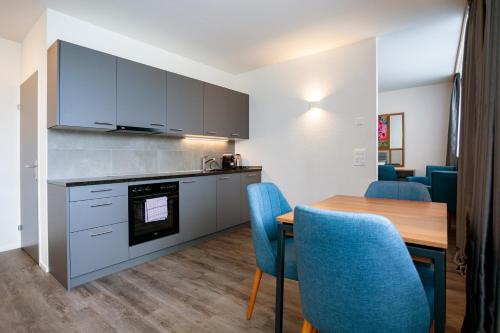 eine Küche und ein Esszimmer mit einem Tisch und blauen Stühlen in der Unterkunft SWAS by Livingdowntown in Zürich