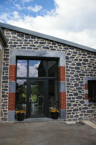 a stone building with a large glass door at Au charme d'antan in Féron