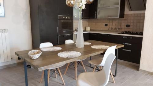 a kitchen with a wooden table and white chairs at La Limonaia Country House in Monteriggioni