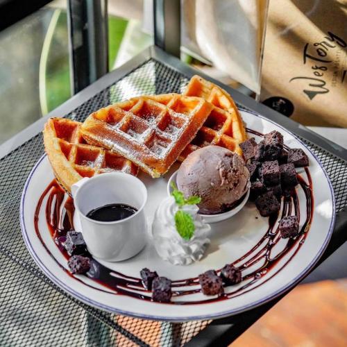 a plate of waffles and ice cream on a table at Westory Design Poshtel in Kanchanaburi