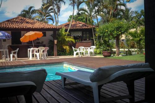 a house with a pool and a deck with chairs and an umbrella at Pousada Solar de Itaúna in Saquarema