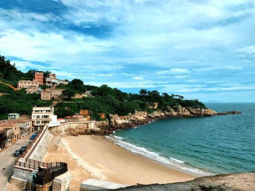 a beach with houses on a hill next to the ocean at Jin Sha Ting Hai Homestay I in Nangan