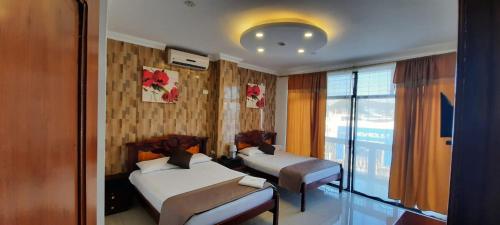 una camera d'albergo con due letti e una finestra di Hostal Perla Real Inn a Guayaquil