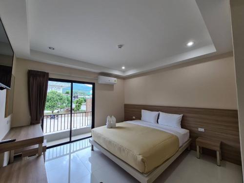 a bedroom with a large bed and a balcony at Grand Maihom Hotel in Chiang Mai