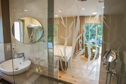 La salle de bains est pourvue d'un lavabo et d'un miroir. dans l'établissement Hotel Weiherhof am Golfpark, à Wadern