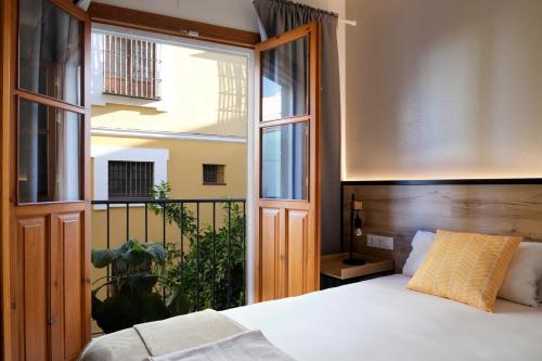 a bedroom with a bed and a large window at Sweet Sevilla Suites in Seville