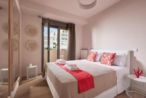 a white bedroom with a large bed with red pillows at Elaia Luxury Apartments Glyfada in Athens