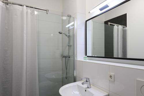 ein Bad mit einem Waschbecken, einer Dusche und einem Spiegel in der Unterkunft Art Rock Downtown Hotel in Köln