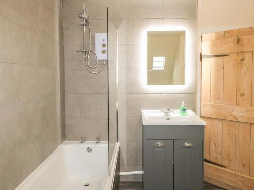 bagno con vasca, lavandino e doccia di Kings Cottage a Grantham