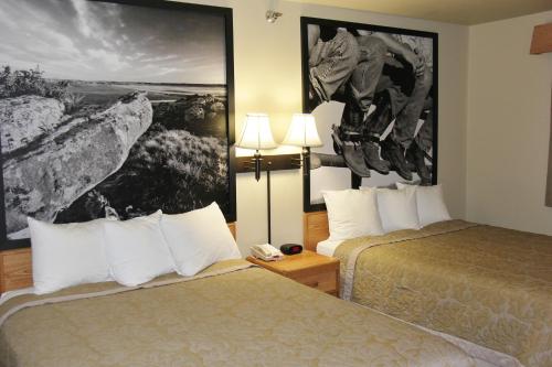 a hotel room with two beds and a picture on the wall at Homestead Inn and Suites in Hardin