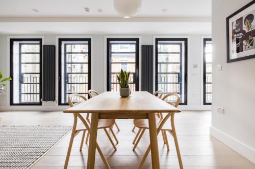 a dining room with a table and chairs and windows at Hausd - Leicester Square in London