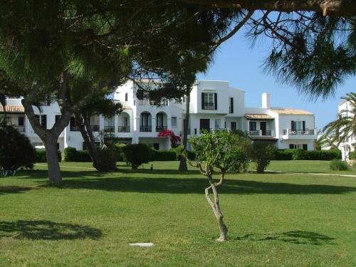 a large white house with trees in front of it at Apartamentos Parque Mar in Cala d´Or