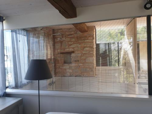 a room with a window with a lamp and a brick wall at Agriturismo Bosimano in Arcevia