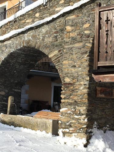 a stone building with an arch in the snow at Lo PONTON in Introd