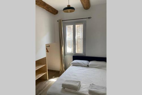 um quarto com uma cama com lençóis brancos e uma janela em Coeur Panier - Charmant T2 entièrement équipé em Marselha