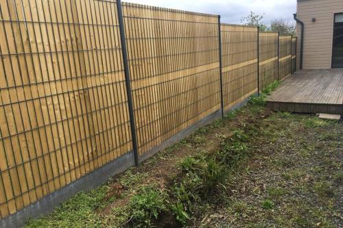 a fence in front of a house with a wooden deck at LES HAUTEURS DE TRESTRAOU in Perros-Guirec
