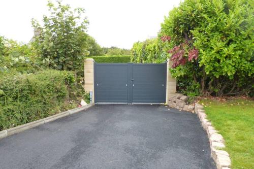 a garage with a blue gate in a driveway at LES HAUTEURS DE TRESTRAOU in Perros-Guirec
