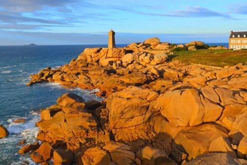 a lighthouse on the edge of a rocky cliff at LES HAUTEURS DE TRESTRAOU in Perros-Guirec