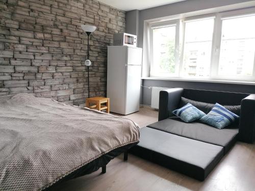 ein Schlafzimmer mit einem Bett, einem Sofa und einer Ziegelwand in der Unterkunft Quiet studio apartment in the city center of Klaipeda in Klaipėda