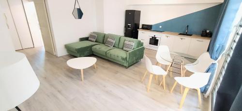 een woonkamer met een groene bank en witte stoelen bij Le Clipper in Saint-Pierre