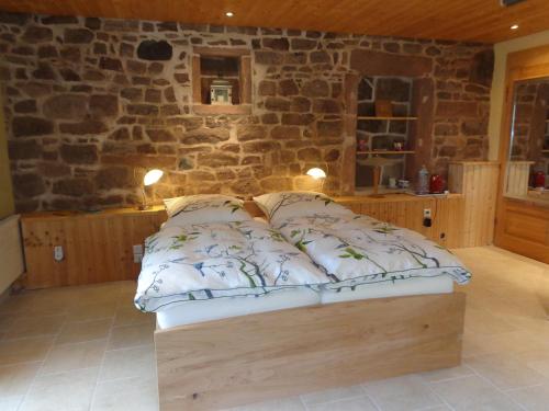 a bed in a room with a stone wall at "La Belle Chambre" dans une ferme avec etang privé dans la région des Mille Etangs Faucogney-et-La-Mer in Écromagny