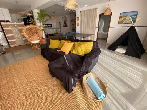 a living room with a black couch and yellow pillows at Bunker 11 Surf House in Charneca