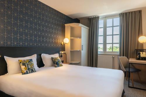 a hotel room with a large bed and a desk at Hôtel Anne d'Anjou, The Originals Collection in Saumur
