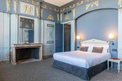a bedroom with a king sized bed and a fireplace at Hôtel Anne d'Anjou, The Originals Collection in Saumur