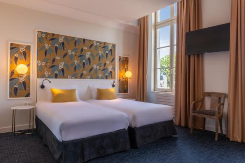 a hotel room with a large bed with yellow pillows at Hôtel Anne d'Anjou, The Originals Collection in Saumur