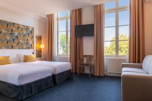 a hotel room with two beds and a chair at Hôtel Anne d'Anjou, The Originals Collection in Saumur