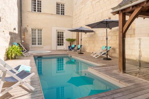 a swimming pool with two chairs and an umbrella at Hôtel Anne d'Anjou, The Originals Collection in Saumur