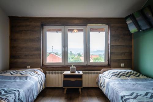 two beds in a room with two windows at Zajazd Izabela in Żywiec