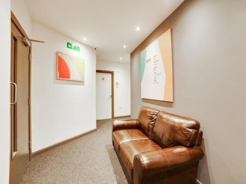 a brown leather couch sitting in a hallway at Snooze Hotel in Corby