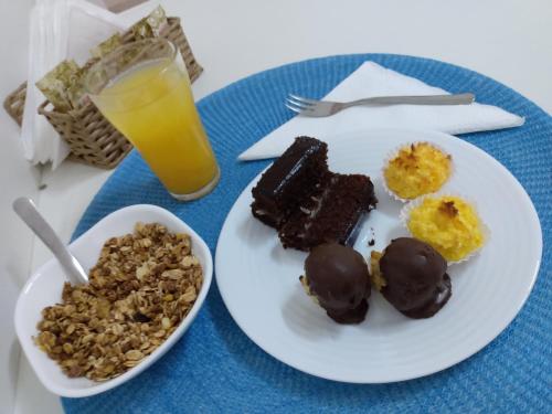 a plate of food with chocolate desserts and a glass of orange juice at Ágape Hotel in Rio Verde