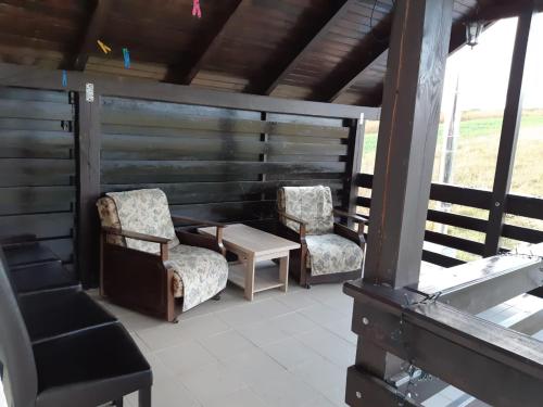 two chairs and a table on a porch at Pensiunea agroturistica Casa Sirca in Boghiş