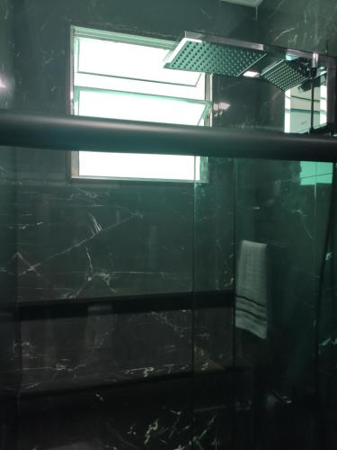 a bathroom with a glass shower with a window at Santa Cecília Pousada in Guarujá