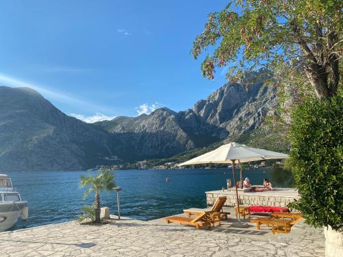 a group of people sitting under an umbrella on a lake at Casa Pasinovic in Kotor