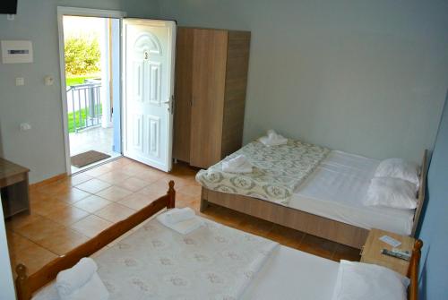 a bedroom with two beds and a door to a balcony at Kremasti Rooms in Kremastí