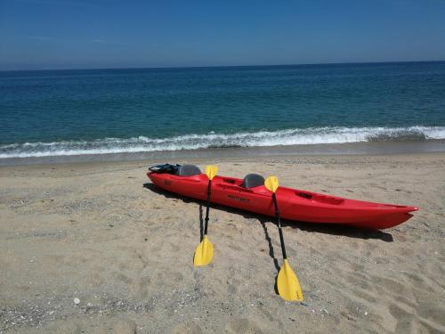 a red kayak sitting on the beach with two paddles at Wonderful family villa with sea view in Byala