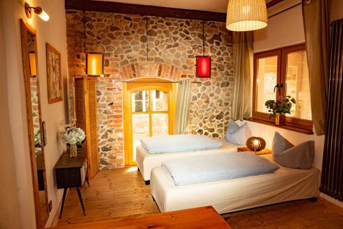 a bedroom with two beds and a stone wall at Brennerei Haselberg in Wriezen