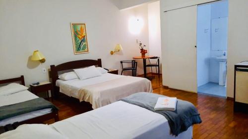 a hotel room with two beds and a table at Hotel Dias - By UP Hotel in Pouso Alegre